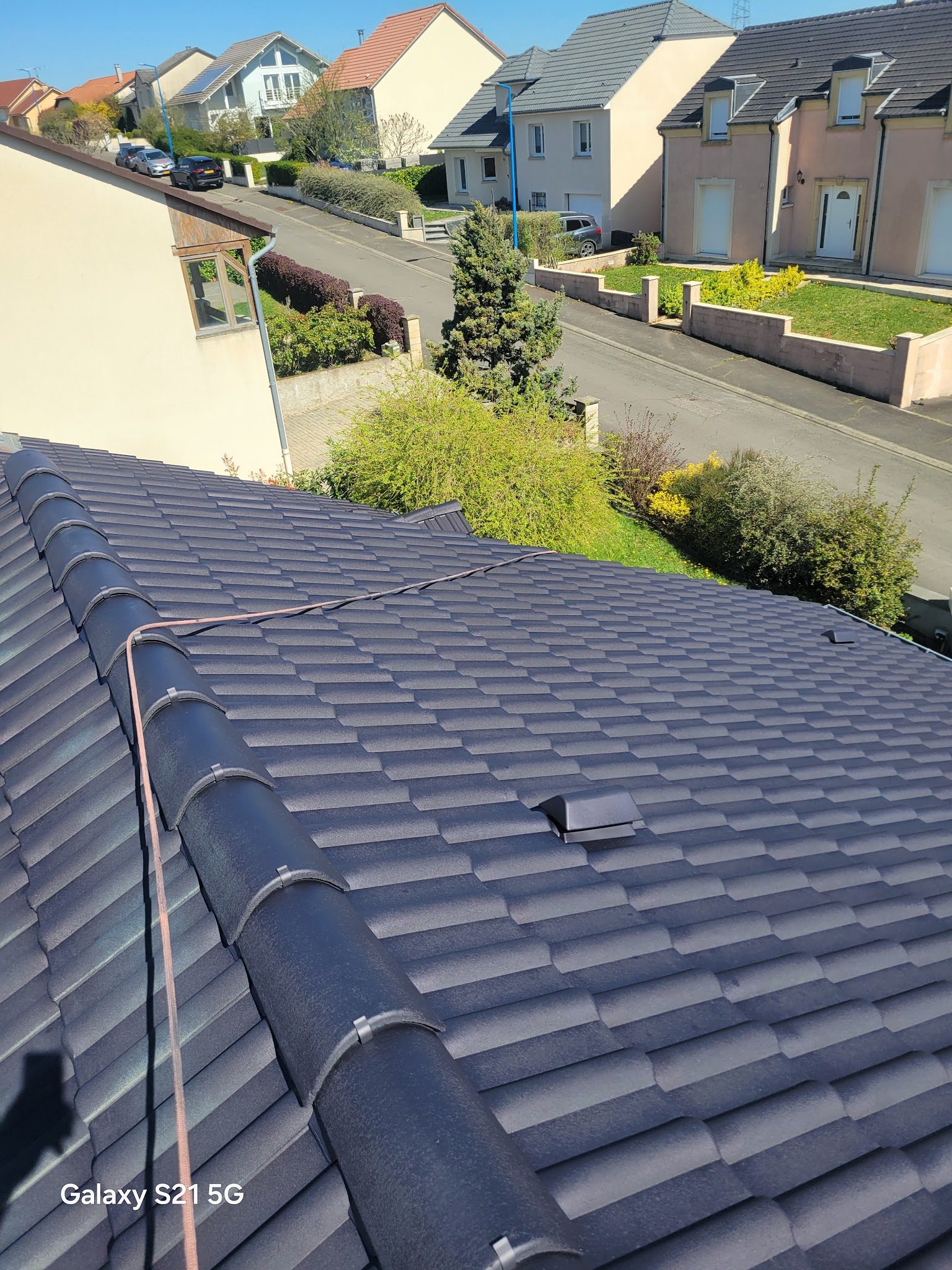 Toit en tuiles anthracite vu du faîtage, rue pavillonnaire en contrebas